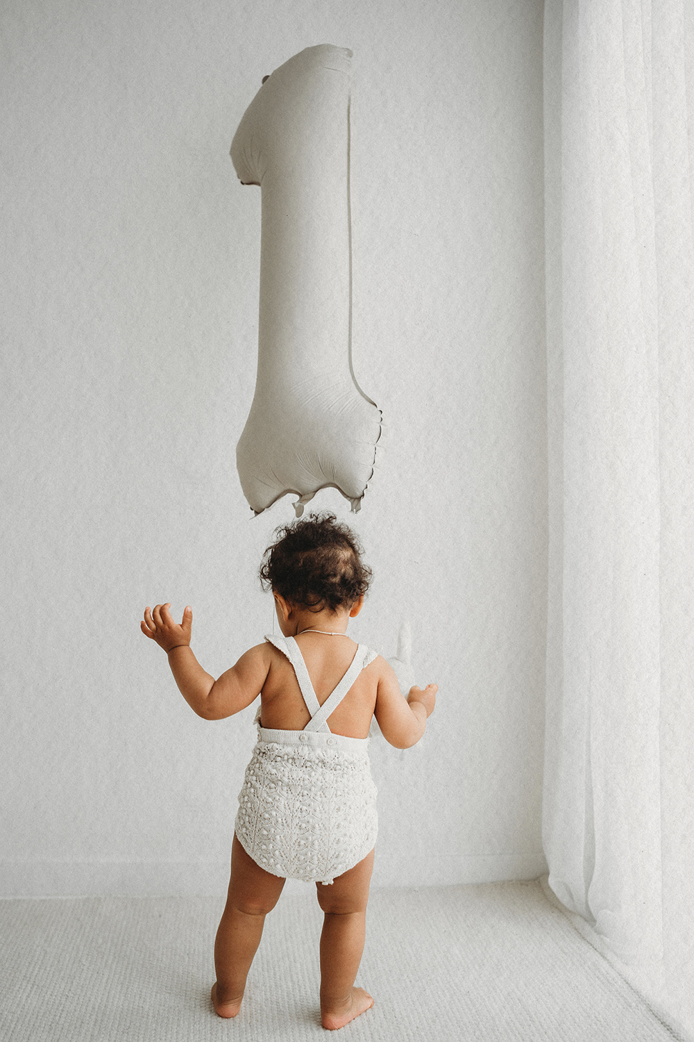 One year shoot in daglichtstudio: kindje dat staat bij een grote "1" ballon. Bij cakesmash Limburg.