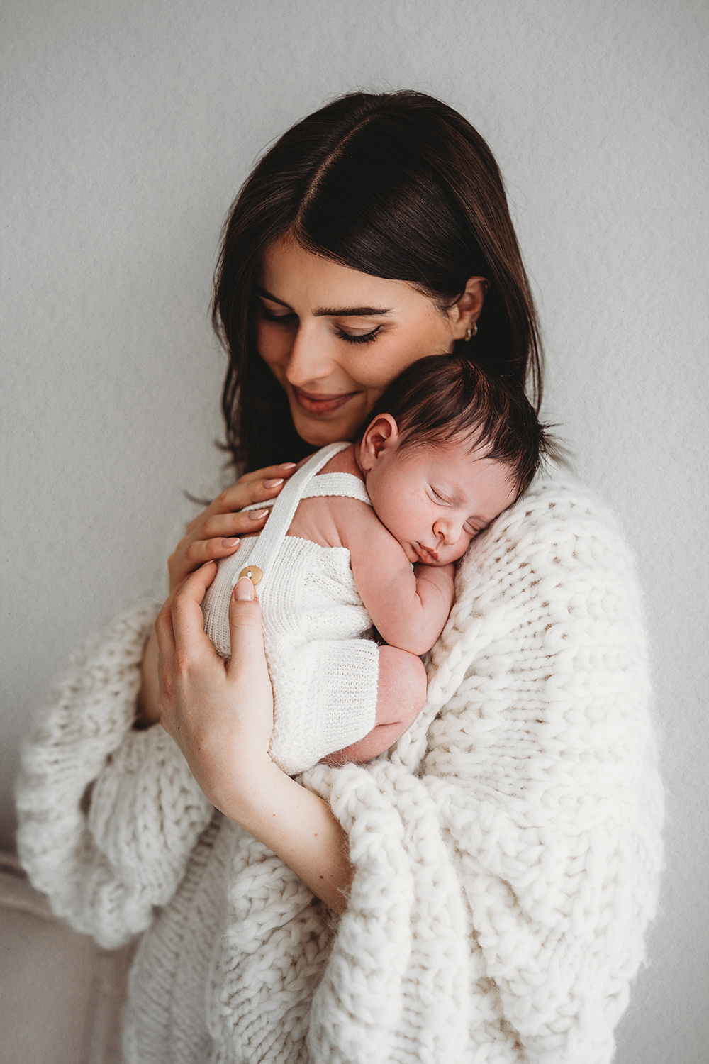 Moeder met slapende newborn tijdens newbornshoot in Limburg.
