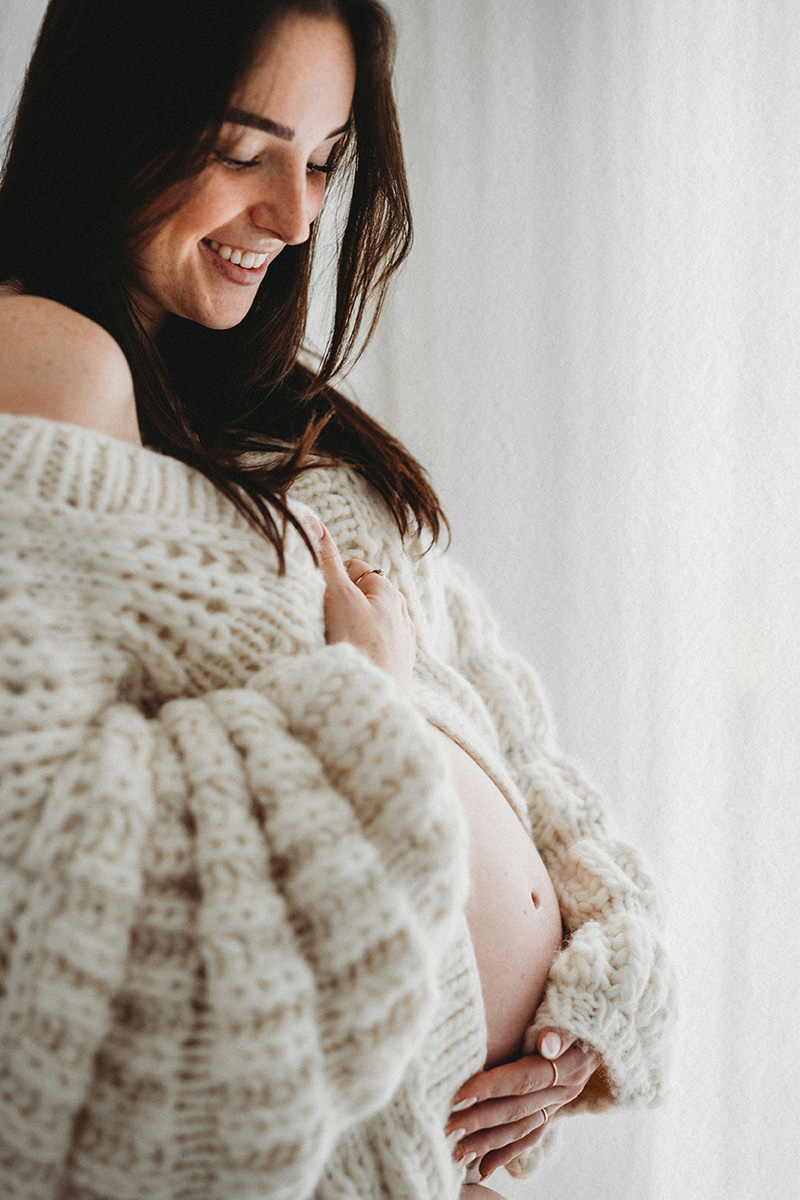 Zwangere vrouw tijdens Zwangerschapsshoot in Limburg bij daglichtstudio, close-up van buik.
