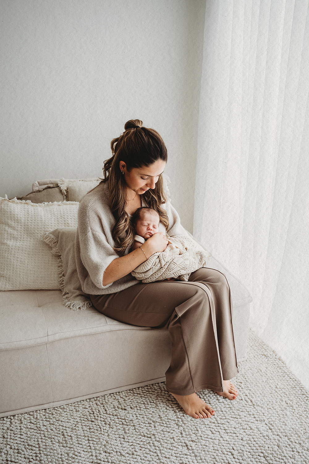 Pasgeboren baby bij de moeder in haar armen tijdens een newborn fotoshoot, passend bij de juiste timing voor newbornfotografie.